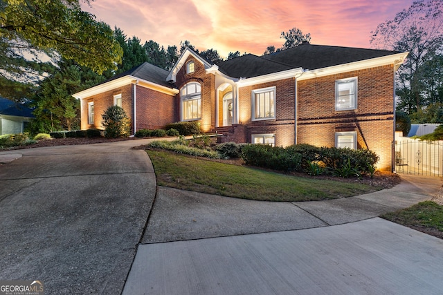 view of front of house featuring driveway, a gate, fence, and brick siding