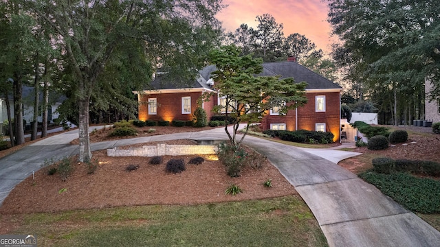 view of front of house featuring driveway, a chimney, and brick siding