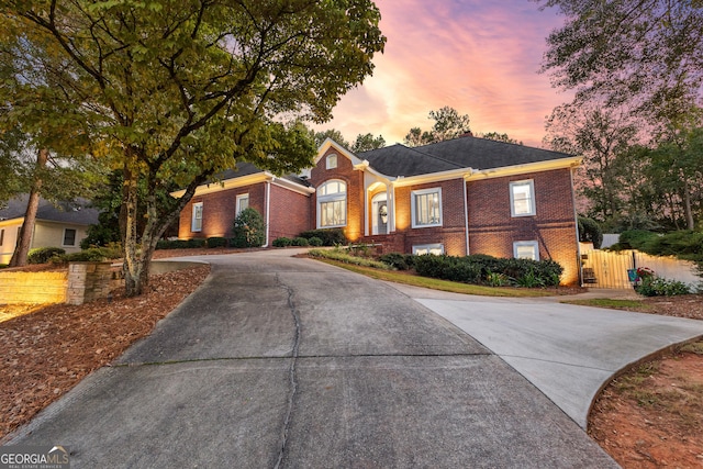 view of front facade featuring driveway, a gate, fence, and brick siding