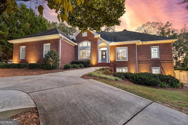 view of front facade with concrete driveway, brick siding, and fence