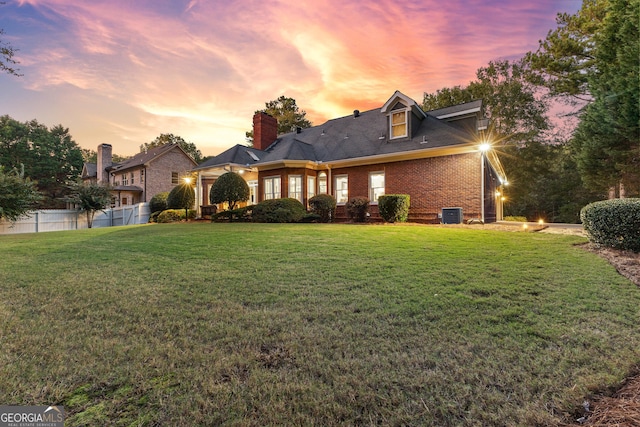 view of front of house with central AC unit, a front yard, fence, and brick siding