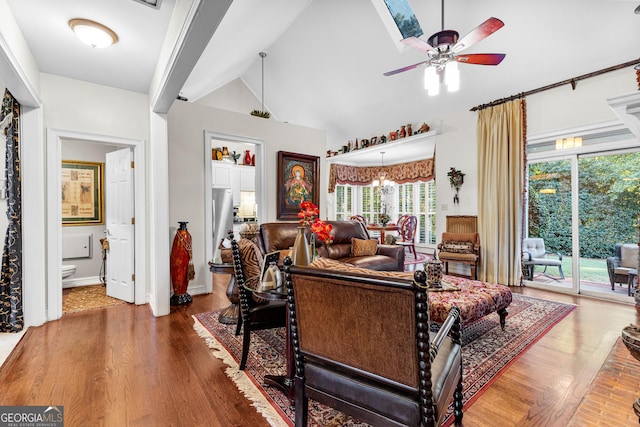 living room featuring ceiling fan with notable chandelier, vaulted ceiling, and wood finished floors