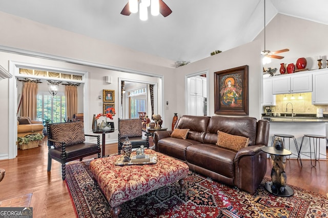 living room featuring lofted ceiling, ceiling fan, light wood-style flooring, and baseboards