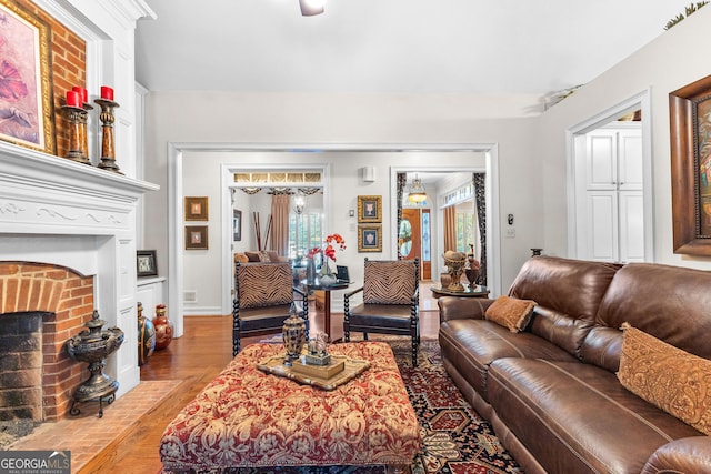 living area with a brick fireplace, baseboards, and wood finished floors