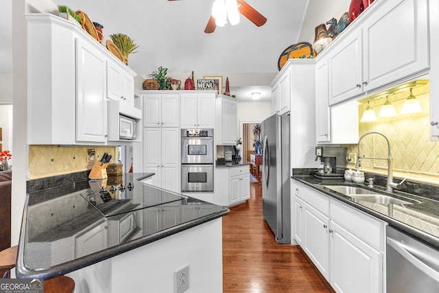 kitchen with stainless steel appliances, decorative backsplash, a sink, and white cabinets