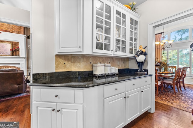 kitchen with white cabinetry, dark wood-style flooring, glass insert cabinets, and a notable chandelier