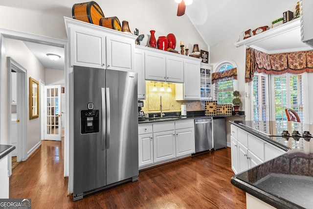 kitchen featuring dark wood-style flooring, stainless steel appliances, lofted ceiling, decorative backsplash, and white cabinetry