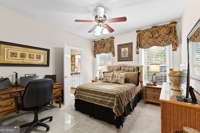 bedroom with a ceiling fan, light carpet, and connected bathroom