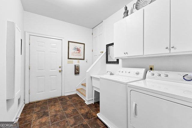 clothes washing area with stone finish floor, independent washer and dryer, cabinet space, and baseboards