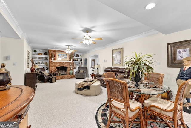 dining space featuring built in shelves, a fireplace, ornamental molding, a ceiling fan, and carpet flooring