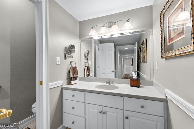 bathroom with toilet, vanity, and baseboards