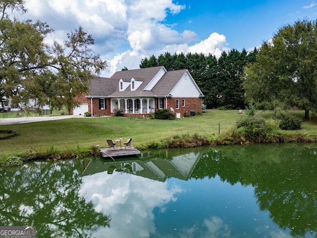 exterior space with a garage, a yard, brick siding, and a water view