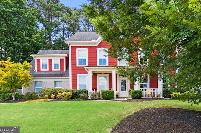 view of front facade with a shingled roof and a front yard