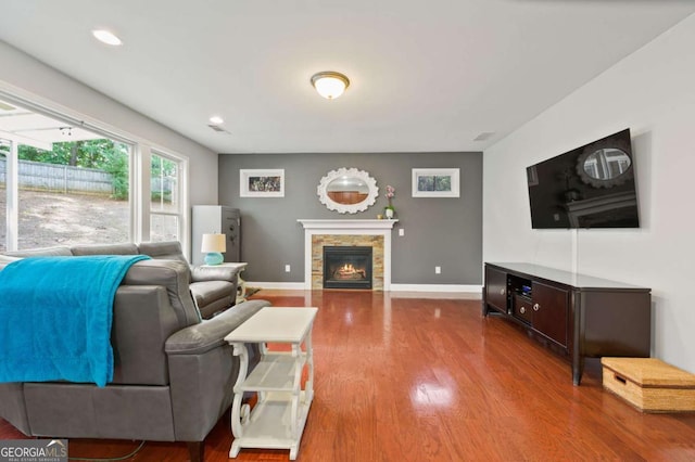 living area featuring recessed lighting, baseboards, wood finished floors, and a stone fireplace