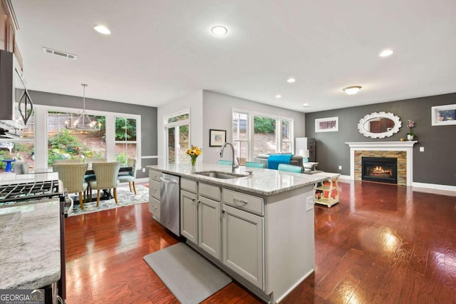 kitchen featuring a stone fireplace, dark wood-type flooring, a sink, appliances with stainless steel finishes, and plenty of natural light