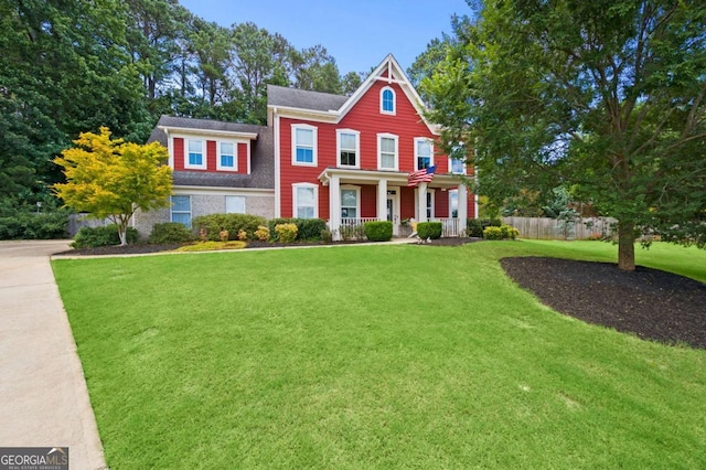 view of front of house featuring a porch, fence, and a front lawn