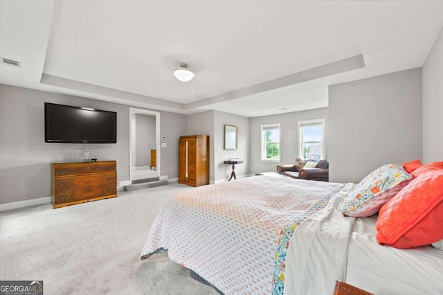 bedroom with carpet, visible vents, a tray ceiling, and baseboards