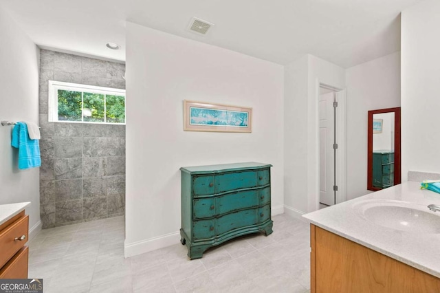 bathroom featuring visible vents, vanity, baseboards, and walk in shower