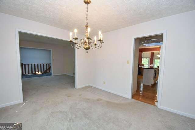 unfurnished dining area featuring a textured ceiling, carpet, a notable chandelier, and baseboards