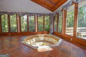 unfurnished sunroom featuring wood ceiling, vaulted ceiling, and a hot tub