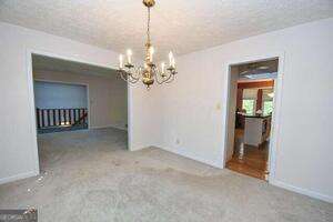 unfurnished dining area featuring a chandelier and a textured ceiling