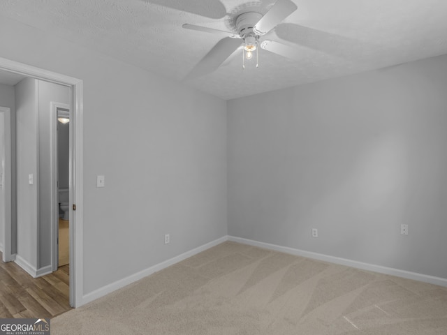 carpeted empty room with a textured ceiling, baseboards, and a ceiling fan