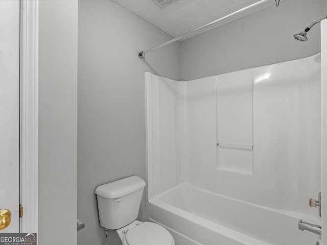 bathroom with a textured ceiling,  shower combination, and toilet