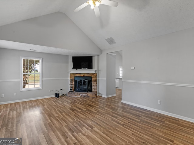 unfurnished living room featuring ceiling fan, a fireplace, wood finished floors, visible vents, and baseboards