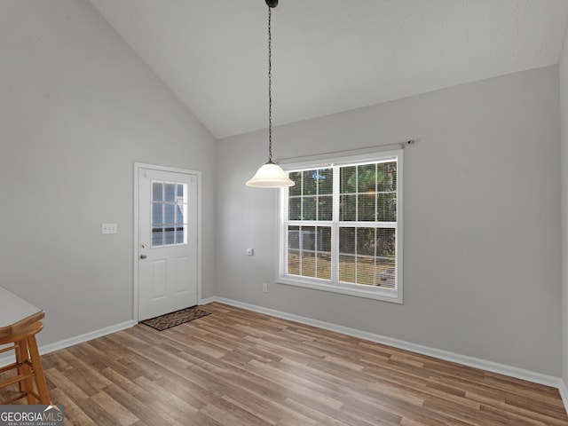 unfurnished dining area featuring vaulted ceiling, wood finished floors, and baseboards