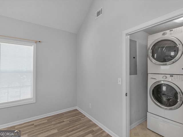 laundry room with stacked washer / drying machine, visible vents, laundry area, electric panel, and baseboards