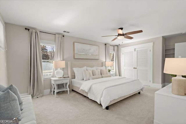 bedroom with light carpet, baseboards, visible vents, ceiling fan, and a closet