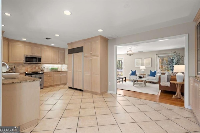 kitchen with appliances with stainless steel finishes, tasteful backsplash, light brown cabinets, and light tile patterned flooring