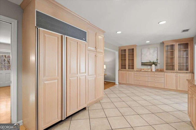 kitchen featuring light tile patterned floors, recessed lighting, light brown cabinetry, glass insert cabinets, and paneled refrigerator