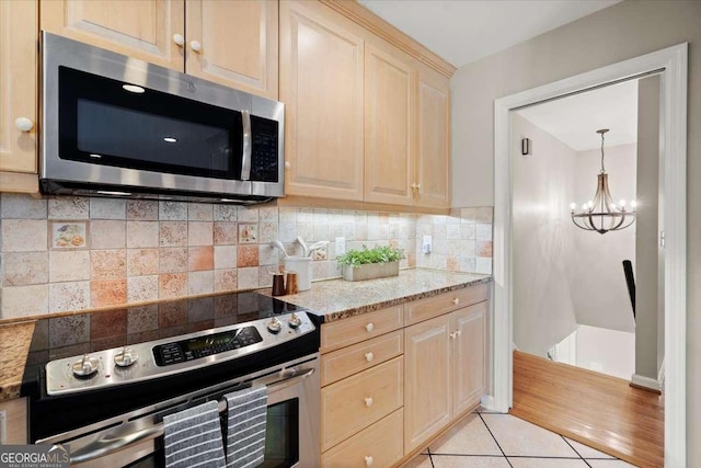 kitchen featuring light tile patterned floors, tasteful backsplash, appliances with stainless steel finishes, light stone counters, and light brown cabinetry