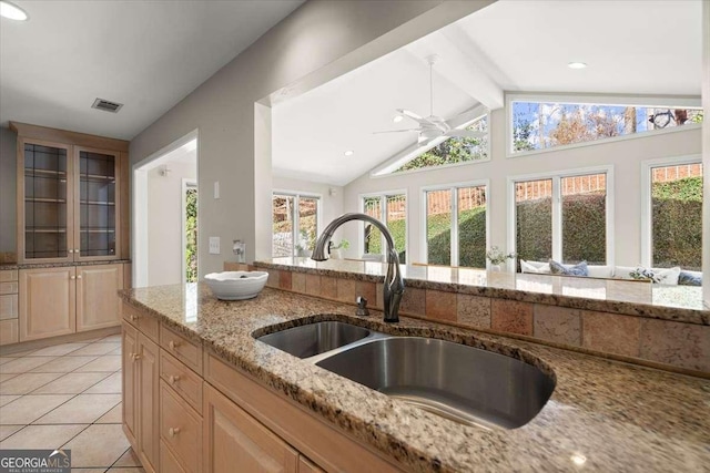 kitchen with vaulted ceiling with beams, light tile patterned floors, a sink, visible vents, and light stone countertops