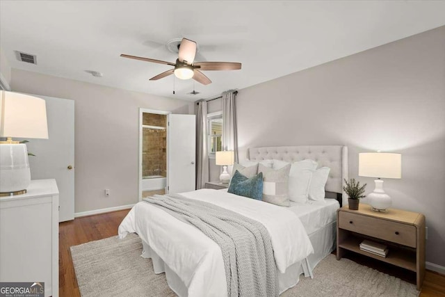 bedroom featuring visible vents, ensuite bathroom, ceiling fan, wood finished floors, and baseboards