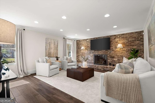 living room featuring crown molding, a fireplace, recessed lighting, brick wall, and wood finished floors