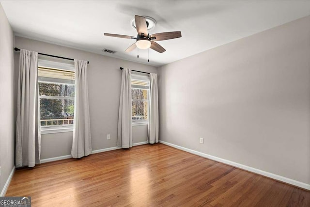 spare room featuring light wood-type flooring, a wealth of natural light, and visible vents