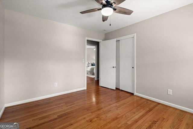 unfurnished bedroom with a closet, ceiling fan, light wood-style flooring, and baseboards