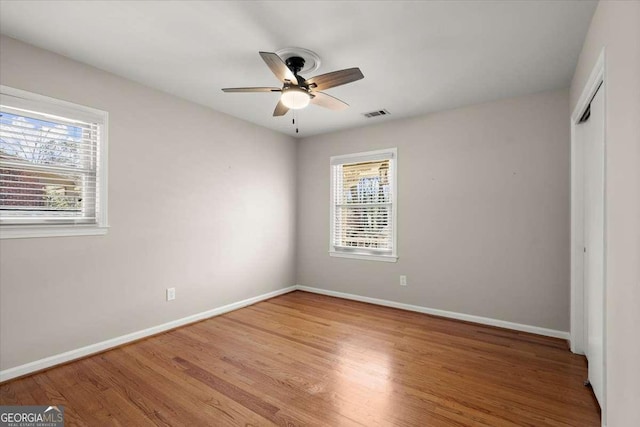 unfurnished bedroom featuring baseboards, a closet, visible vents, and wood finished floors