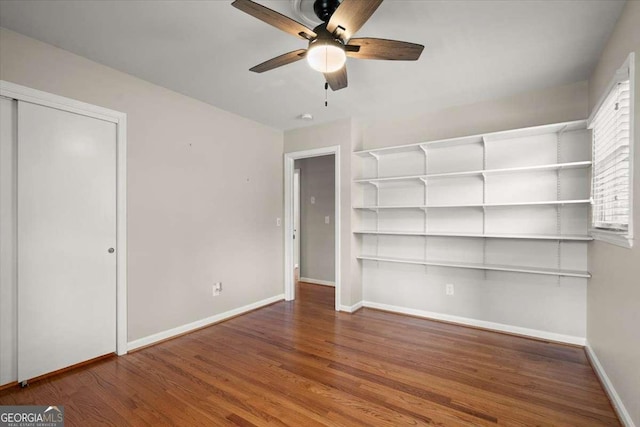 empty room with a ceiling fan, baseboards, and wood finished floors