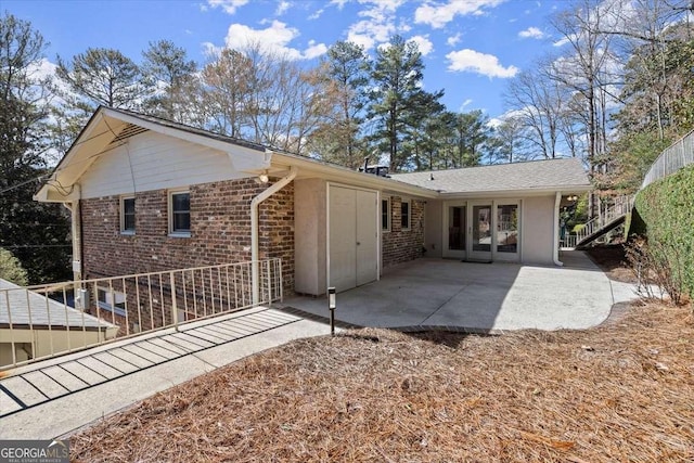 rear view of property featuring brick siding, a patio, and french doors