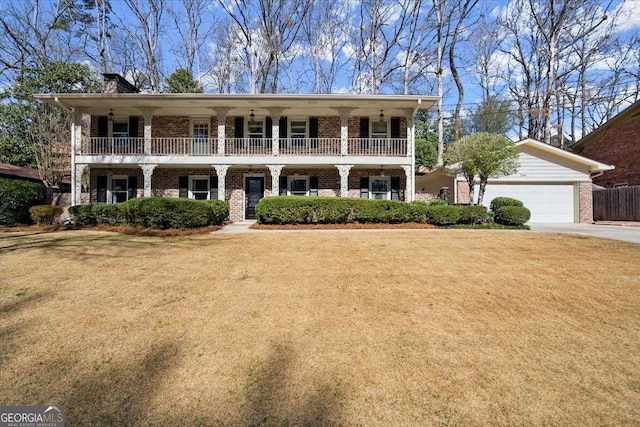 view of front of home featuring an attached garage, a balcony, brick siding, concrete driveway, and a front yard