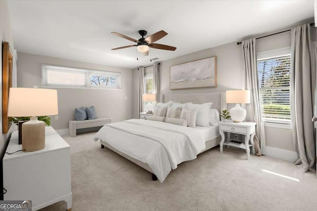 carpeted bedroom with multiple windows, a ceiling fan, and baseboards