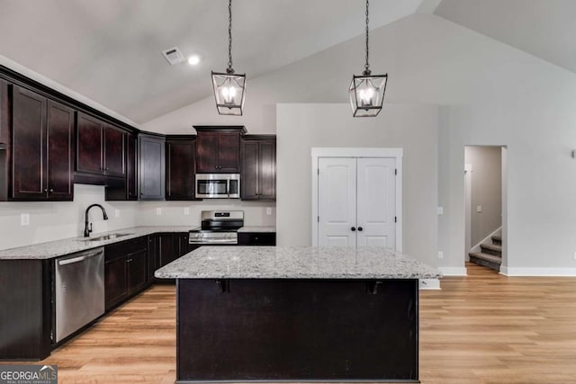 kitchen with a center island, light wood finished floors, stainless steel appliances, visible vents, and a sink