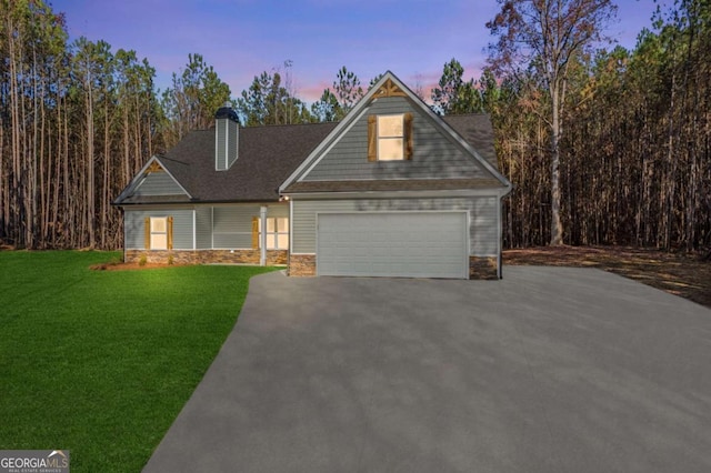 view of front of home with a yard, stone siding, an attached garage, and driveway