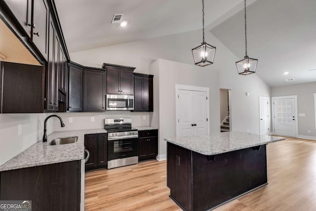 kitchen featuring light wood finished floors, visible vents, a kitchen island, appliances with stainless steel finishes, and a sink