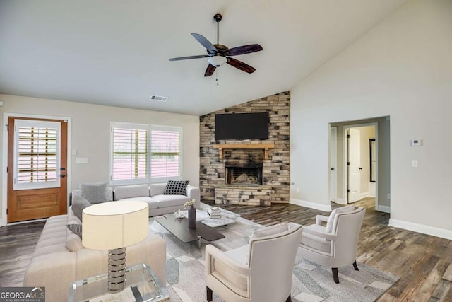 living room featuring a fireplace, wood finished floors, visible vents, baseboards, and a ceiling fan