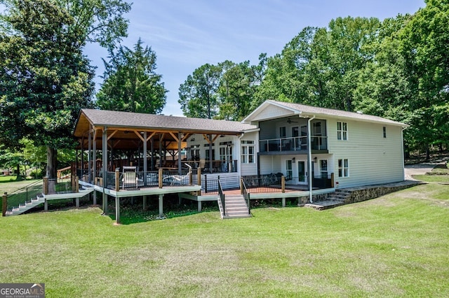 back of property featuring ceiling fan, stairway, a lawn, a balcony, and a deck