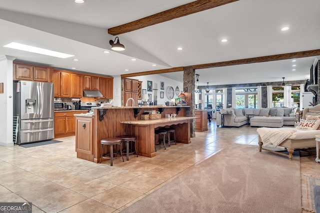 kitchen with a breakfast bar, lofted ceiling with beams, recessed lighting, light tile patterned flooring, and stainless steel appliances
